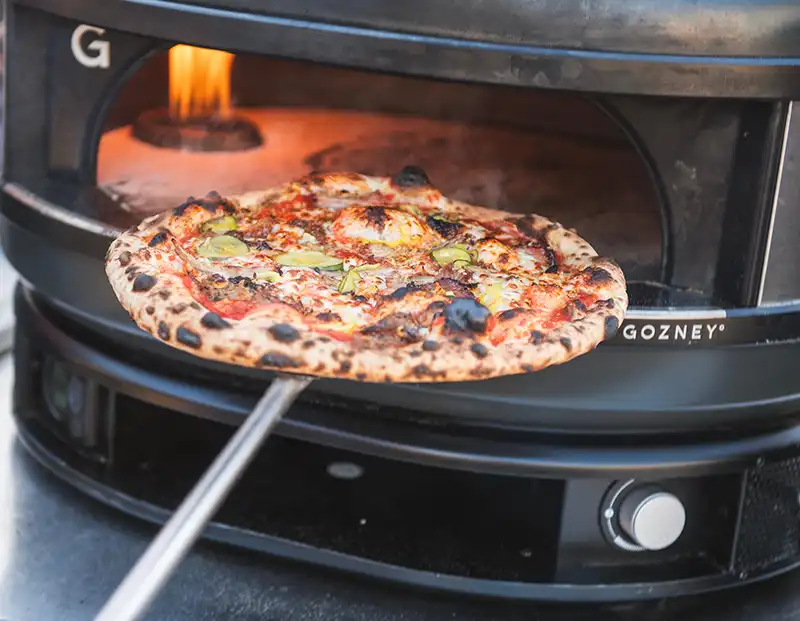 A pizza being cooked in a wood-fired oven